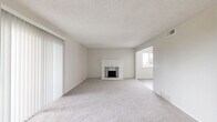 Located at 13050 W Cedar Dr in Lakewood, Colorado, this single-floor 2-bedroom, 2-bathroom home offers a well-organized layout designed for comfortable everyday living. The living room serves as the heart of the space, anchored by a white-painted brick fireplace with a decorative iron screen. Large sliding glass doors flood the area with natural light and provide direct access to the outdoors, while a secondary window adds additional brightness. Soft, neutral carpeting runs throughout the living areas and bedrooms, contributing to a warm and cohesive aesthetic. The kitchen stands out with crisp white shaker cabinetry, granite-look countertops, a stainless steel sink, and a full suite of stainless steel appliances including a range, over-the-range microwave, and refrigerator. Light wood-look flooring completes the kitchen's clean, modern feel. The primary bedroom is a well-proportioned retreat with a window overlooking greenery and sliding glass door access. The second bedroom also features plush carpeting and a bright window. Both bathrooms are finished with granite-topped vanities and wood-look tile flooring. A textured ceiling is present throughout, and the layout includes a dedicated closet for added storage.