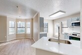 This well-appointed single-story home offers four bedrooms and two bathrooms across a comfortable and efficiently designed floor plan. The living room serves as a welcoming centerpiece, featuring a tiled fireplace, crown molding, a ceiling fan, and light wood-look flooring that flows throughout the home. Natural light filters in through windows, enhancing the bright, neutral palette of the space.

The kitchen has been thoughtfully updated with slate-blue shaker cabinetry, marble-look tile backsplash, quartz countertops, a gold-tone pull-down faucet, and stainless steel appliances including a range, microwave, and French door refrigerator. A skylight above the kitchen adds an abundance of natural light, while a peninsula provides additional prep and serving space.

The primary bedroom is generously sized and includes a ceiling fan and access to a walk-in closet with wire shelving. The bathrooms are finished with elegant marble-look surround tiling and a soaking tub. The additional bedrooms are well-proportioned, each with ceiling fans and ample closet space.

Connecting the rooms are arched hallways that add architectural character. A dedicated laundry room with washer hookups and shelving rounds out the functional layout of this comfortable home.