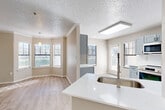 This well-appointed single-story home offers four bedrooms and two bathrooms across a comfortable and efficiently designed floor plan. The living room serves as a welcoming centerpiece, featuring a tiled fireplace, crown molding, a ceiling fan, and light wood-look flooring that flows throughout the home. Natural light filters in through windows, enhancing the bright, neutral palette of the space.

The kitchen has been thoughtfully updated with slate-blue shaker cabinetry, marble-look tile backsplash, quartz countertops, a gold-tone pull-down faucet, and stainless steel appliances including a range, microwave, and French door refrigerator. A skylight above the kitchen adds an abundance of natural light, while a peninsula provides additional prep and serving space.

The primary bedroom is generously sized and includes a ceiling fan and access to a walk-in closet with wire shelving. The bathrooms are finished with elegant marble-look surround tiling and a soaking tub. The additional bedrooms are well-proportioned, each with ceiling fans and ample closet space.

Connecting the rooms are arched hallways that add architectural character. A dedicated laundry room with washer hookups and shelving rounds out the functional layout of this comfortable home.
