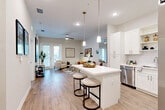 Located at 1387 East Vine Street in Kissimmee, FL, this thoughtfully designed one-bedroom, one-bathroom residence offers a bright, modern living experience on a single floor. The open-concept layout seamlessly connects the kitchen, dining, and living areas, creating a cohesive and airy space ideal for both relaxing and entertaining. Light wood-tone flooring flows throughout, complementing the neutral color palette and contemporary design.

The kitchen is a standout feature, showcasing crisp white shaker cabinetry that extends to the ceiling, stainless steel appliances including a full-size refrigerator, microwave, and dishwasher, and a central island with pendant lighting and bar seating — perfect for casual dining. The living area benefits from natural light streaming through French doors, which open to the outside, while a ceiling fan adds comfort overhead.

The generously sized bedroom offers a tranquil retreat with a large window, ample natural light, and direct sightlines to a walk-in closet. The full bathroom impresses with marble-look tile flooring and wall surround in the glass-enclosed shower, a wide vanity with ample storage, and clean, upscale finishes. The home also includes a dedicated laundry area and utility room, adding everyday convenience to this polished Kissimmee residence.