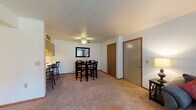 This single-floor residence at 1880 Raleigh Ave in Kendallville, Indiana, offers a well-organized layout designed for comfortable everyday living. The living room serves as a central gathering space, featuring plush carpeting, a large sliding glass door with vertical blinds that invites natural light and provides outdoor views, and a wall-mounted air conditioning unit for climate control.

Adjacent to the living room, the dining area is a defined space anchored by a ceiling fan with a light fixture overhead. A mirrored wall accent enhances the sense of openness, while a closet nearby adds convenient storage. The kitchen follows a galley-style configuration with wood-look flooring, white cabinetry with warm wood trim, and white appliances including a range, refrigerator, and dishwasher, providing efficient functionality.

The bedroom offers carpeted flooring, natural light through a window with outdoor views, and generous storage via multiple closets, including a dedicated laundry area. The full bathroom features wood-look flooring, an extended vanity with a single sink, open shelving, and a shower-tub combination. Throughout the residence, neutral tones and clean lines create a practical and cohesive living environment.