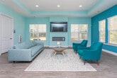 Located at 1201 Summerwood Dr in Clarkston, Georgia, this single-floor community clubhouse is designed with a cohesive, contemporary aesthetic that blends comfort and functionality. The interior is defined by its signature palette of soft aqua and bold teal wall tones, complemented by wood-look flooring and crisp white trim throughout.

The main lounge area serves as the heart of the space, furnished with a light gray sofa, deep teal accent chairs, and a round wooden coffee table centered on a patterned area rug. A wall-mounted flat-screen television sits above a sleek linear fireplace, flanked by multiple windows that invite abundant natural light and offer views of the surrounding outdoor amenities, including what appears to be a pool area.

The space flows openly into additional seating and transition zones, where a teak-toned credenza and curated artwork add character. Recessed lighting and tray ceiling details lend a polished architectural finish. A glass-panel French door leads to a private office or meeting room, providing a dedicated workspace within the broader communal layout. The overall ambiance is welcoming, bright, and thoughtfully appointed for both relaxation and community engagement.
