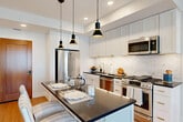 Located on the 24th floor at 7316 Wisconsin Avenue in the heart of Bethesda, Maryland, this one-bedroom, one-bathroom residence offers a well-designed layout with modern finishes throughout. Warm hardwood flooring flows seamlessly through the open-plan kitchen and living area, creating a cohesive and inviting atmosphere.

The kitchen is outfitted with white shaker cabinetry, dark countertops, a marble-style tile backsplash, and a full suite of stainless steel appliances including a gas range, dishwasher, and refrigerator. A center island with pendant lighting provides additional prep space and casual seating, making it ideal for both cooking and entertaining.

The living room is bathed in natural light through expansive floor-to-ceiling windows that frame striking high-rise views of the Bethesda skyline. The neutral palette and clean architectural lines lend the space a calm, contemporary feel.

The bedroom is a tranquil retreat, featuring large windows with the same captivating city views, light hardwood floors, and ample room for a full furniture arrangement. The bathroom is finished with classic black-and-white mosaic tile flooring, white cabinetry with brushed nickel hardware, and a clean, timeless aesthetic. Two hallways provide functional circulation and additional storage opportunities throughout the residence.