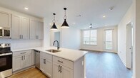 Located at 95 Plum Nelly Cir in Nashville, TN, this well-appointed two-bedroom, two-bathroom residence offers a thoughtfully designed single-floor layout. The open-concept kitchen and living area serves as the heart of the home, featuring warm wood-look flooring, recessed lighting, and stylish black pendant lights. The kitchen is outfitted with gray shaker-style cabinetry, stainless steel appliances including a French door refrigerator, electric range, and microwave, complemented by a quartz-topped island with an undermount sink. The living room benefits from natural light streaming through large windows, a ceiling fan, and direct access to a private outdoor area. Both bedrooms are carpeted for comfort, with the generously sized primary bedroom offering ample space. The two bathrooms are finished with quartz countertops and wood-look tile flooring; one features a glass-enclosed walk-in shower with white subway tile, while the other includes a full soaking tub. Two closets provide well-organized storage with wire shelving systems. A dedicated laundry area adds everyday convenience. Clean neutral tones and modern hardware throughout create a cohesive, contemporary aesthetic.