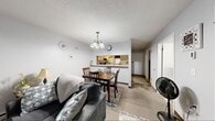 Located at 1279 Coffeen Street in Watertown, New York, this single-floor residence offers a practical and well-organized layout designed for comfortable everyday living. The living room features neutral-toned carpet, light gray walls, and a large window dressed with sheer curtains that allow natural light to fill the space. A baseboard heating unit runs along the wall, providing efficient warmth. Adjacent to the living area, the dining space is defined by a pendant chandelier overhead and connects seamlessly to the kitchen via a pass-through counter opening, creating an open and communicative flow between rooms. The kitchen is equipped with cream-toned cabinetry, ample counter space, a stainless steel range, dishwasher, and tile flooring, offering a fully functional cooking environment. The bedroom is a comfortable retreat featuring multiple windows that bring in natural light, soft carpeting, and a textured ceiling. The bathroom includes a vanity with under-sink cabinetry, a wall-mounted mirror with overhead lighting, and tile flooring, with a shower-tub combination enclosed by a curtain. Throughout the residence, a consistent neutral color palette and straightforward design create a cohesive and inviting atmosphere.
