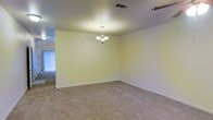 This two-floor home offers a straightforward and functional layout designed to accommodate everyday living with ease. The interior is finished with wall-to-wall carpeting throughout the main living areas, providing a warm and comfortable underfoot feel. A standout feature of the main living or dining area is the classic chandelier suspended from the ceiling, adding a touch of elegance to the otherwise clean and neutral space. The walls are painted in a soft, light tone that contributes to a bright and airy atmosphere, while the ceiling-mounted ventilation ensures consistent climate control throughout. Natural light filters into the space through nearby windows, enhancing the open feel of the room. The layout flows naturally between rooms, making the space feel connected and easy to navigate. With two floors, the home provides a natural separation between living and private spaces, offering both communal areas for gathering and more secluded spaces for rest. The overall ambiance is clean, neutral, and move-in ready, providing a versatile canvas for a variety of interior styles and personal touches.