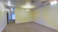 This two-floor home offers a straightforward and functional layout designed to accommodate everyday living with ease. The interior is finished with wall-to-wall carpeting throughout the main living areas, providing a warm and comfortable underfoot feel. A standout feature of the main living or dining area is the classic chandelier suspended from the ceiling, adding a touch of elegance to the otherwise clean and neutral space. The walls are painted in a soft, light tone that contributes to a bright and airy atmosphere, while the ceiling-mounted ventilation ensures consistent climate control throughout. Natural light filters into the space through nearby windows, enhancing the open feel of the room. The layout flows naturally between rooms, making the space feel connected and easy to navigate. With two floors, the home provides a natural separation between living and private spaces, offering both communal areas for gathering and more secluded spaces for rest. The overall ambiance is clean, neutral, and move-in ready, providing a versatile canvas for a variety of interior styles and personal touches.