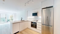 Located at 150 Roehampton Ave in Toronto's vibrant Midtown neighbourhood, this 1-bedroom, 1-bathroom unit offers a thoughtfully designed open-concept layout with clean, modern finishes throughout. Light hardwood flooring runs continuously across the space, complementing the bright, white palette that defines every room.

The kitchen and living area share an open, connected footprint anchored by a sleek peninsula with a marble-veined stone countertop and an undermount sink with a matte black faucet. The kitchen is outfitted with flat-front white cabinetry extending to the ceiling, a marble-tile backsplash, stainless steel appliances including a built-in oven, microwave, and refrigerator, and a glass-top cooktop. Track lighting overhead adds a contemporary touch. Floor-to-ceiling sliding glass doors flood the living area with abundant natural light and offer open views of the surrounding cityscape and greenery.

The bedroom is a serene, sunlit space with the same light hardwood flooring and crisp white walls. Two closets provide generous storage. The bathroom features a marble-topped vanity with an undermount sink, a combined soaking tub and shower with matte black fixtures, and a clean, frameless black-trimmed glass enclosure. Every detail reflects a cohesive, modern aesthetic ideal for contemporary urban living.