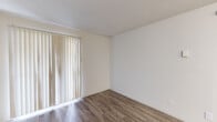 This one-bedroom, one-bathroom unit in Houston, TX offers a well-organized single-floor layout that makes efficient use of its compact footprint. The living area features warm wood-look vinyl flooring and vertical blinds that allow natural light to filter through, creating a bright and inviting atmosphere. The kitchen is equipped with white cabinetry, a tasteful subway tile backsplash, a stainless steel sink, and black appliances including a refrigerator, dishwasher, and range — providing a functional cooking space with light vinyl flooring. The bedroom is a comfortable retreat featuring plush carpet, a ceiling fan with light fixture, and a window with outdoor views, offering both comfort and ventilation. A dedicated closet provides convenient storage. The bathroom is finished in a clean, all-white palette, featuring a shower-tub combo with tiled surround, a white vanity with storage cabinet, a large mirror, and wood-look flooring that ties the space together cohesively. Throughout the unit, neutral wall tones and consistent flooring choices create a cohesive, understated aesthetic well-suited for comfortable everyday living in the Houston area.