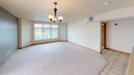 This single-floor unit offers a practical and well-organized layout designed for comfortable everyday living. The open-concept living and dining area is finished with soft wall-to-wall carpeting and features a chandelier light fixture, a textured ceiling, and a large window that allows natural light to fill the space, creating a bright and welcoming atmosphere.

The kitchen flows seamlessly from the living area and is equipped with light wood cabinetry, laminate countertops, a peninsula with a single-basin sink, and white appliances including a refrigerator, electric range, and built-in microwave. Tile flooring grounds the kitchen and extends into the adjoining areas, providing a clean transition between spaces.

Two carpeted bedrooms each offer individual windows with blinds that bring in natural light while maintaining privacy. Both rooms feature neutral walls, wood baseboards, and textured ceilings with flush-mount light fixtures, providing a calm and functional environment.

The full bathroom includes a toilet and a combined shower and bathtub unit, finished with tile flooring and neutral wall tones. A dedicated in-unit laundry room houses a full-size top-loading washer and dryer, complemented by an overhead wire shelving rack for additional storage. Throughout, the unit maintains a consistent neutral color palette and clean, functional finishes.