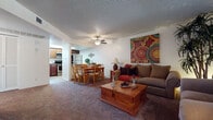 This single-floor residence offers a thoughtfully designed layout that balances comfort and functionality throughout its key living spaces. The open-concept living and dining area serves as the heart of the home, featuring plush wall-to-wall carpeting, a textured ceiling, and a ceiling fan that enhances air circulation. The living room provides ample space for seating and is brightened by a large window with vertical blinds that allows natural light to fill the room. Vibrant wall art adds a warm, inviting character to the space. The dining area flows seamlessly from the living room, offering a dedicated space for meals just steps from the kitchen. The kitchen is well-equipped with rich dark wood cabinetry, dark granite countertops, wood-look tile flooring, and full appliances including a refrigerator, stove, and microwave. The bedrooms are carpeted and include windows with vertical blinds, offering natural light and a tranquil atmosphere. Both bathrooms are finished consistently with dark wood vanities, granite countertops, wood-look flooring, and shower-tub combinations. One bathroom features a full vanity mirror and decorative accents, while the second offers a clean, functional layout. Throughout the residence, the cohesive design elements and warm tones create a comfortable and welcoming living environment.