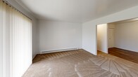 Located at 3372 Van Horn Rd in Trenton, Michigan, this 2-bedroom, 1-bathroom unit offers a functional and well-organized single-floor layout. The entrance opens to a hallway that connects the main living areas, with hardwood-style flooring running through the common spaces and plush carpet in the bedrooms and living room. The combined kitchen and dining area is equipped with dark wood cabinetry, ample counter space, a double sink, an electric range, and a refrigerator, along with an adjacent pantry for additional storage. The living room is generously sized, featuring sliding glass doors with vertical blinds that allow natural light to fill the space, alongside a wall-mounted air conditioning unit. Both bedrooms are carpeted and include natural light from windows, baseboard heating, and closet access — the primary bedroom offering a notably spacious footprint. The bathroom stands out with a wide dual-sink vanity, dark countertops, wood cabinetry, and hardwood-style flooring. Throughout the unit, an impressive five closets provide exceptional storage capacity. Clean white walls and consistent finishes give the space a bright, neutral aesthetic suited for a variety of living arrangements.