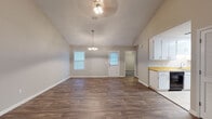 Located at 2840 Rosehill Dr in Tifton, Georgia, this single-story home offers a thoughtfully designed layout with a blend of functional and inviting spaces. The open living and dining area is a standout feature, showcasing soaring vaulted ceilings that create an expansive, airy feel. Rich, dark hardwood-style flooring flows throughout these main areas, complemented by neutral-toned walls and an elegant chandelier overhead. Natural light filters in through multiple windows, including a charming bay window that adds architectural character to the living space. A ceiling fan provides year-round comfort in both the living and dining zones. The kitchen is well-appointed with abundant white cabinetry, warm wood-toned countertops, light tile flooring, and black appliances including a range with overhead microwave and a full-size refrigerator — offering ample storage and workspace for cooking. The bedroom features plush carpeting, a ceiling fan, a textured ceiling, and a window that lets in natural light, providing a cozy and restful retreat. The bathroom is clean and functional, finished with tile flooring, a single vanity with a mirror, and a shower-tub combination. Throughout the home, consistent neutral tones and practical finishes create a cohesive, move-in-ready atmosphere.