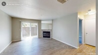 This one-bedroom, one-bathroom apartment at Brookside Apartments in Carmichael, California offers a well-designed single-level layout with a functional and comfortable floor plan. The living room serves as the heart of the home, featuring wood-style laminate flooring, a tile-surround fireplace, and a sliding glass door that floods the space with natural light while providing access to an outdoor patio area with views of surrounding greenery. A ceiling fan in the adjoining area adds both style and practicality. The kitchen is thoughtfully appointed with white shaker-style cabinetry, light stone-look countertops, stainless steel appliances including an electric range, and a stainless steel sink — all set atop matching wood-style flooring for a clean, cohesive aesthetic. The bedroom is carpeted for comfort, features a standard window with blinds for natural light and privacy, and includes a ceiling fan overhead. A generously sized walk-in closet with dual hanging rods provides ample storage. The bathroom is neatly finished with a white vanity, large wall mirror, modern light fixture, and wood-style flooring. Neutral tones throughout the unit create a bright and welcoming atmosphere.