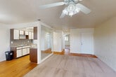 Located in Fort Myers, FL, this single-story, one-bedroom, one-bathroom residence offers a practical and comfortable layout across a well-utilized floor plan. The open-concept living area seamlessly integrates the dining room, kitchen, and living room, all united by warm hardwood-style flooring. Ceiling fans are present throughout the home, promoting airflow and comfort in the Florida climate. The galley-style kitchen is efficiently designed with white cabinetry accented by wood-tone details, granite-style countertops, a double sink, and white appliances including a coil-top electric range and refrigerator. A pendant light fixture illuminates the adjacent dining area, which receives natural light from a window overlooking the surroundings. The spacious living room features plush carpeting and a mirrored wall panel that enhances the sense of openness. A hallway connects the main living spaces to the private bedroom, which is generously sized and carpeted, offering two mirrored sliding-door closets and a window with views of mature Florida palms. The full bathroom is appointed with mosaic tile flooring, a granite-style vanity, and a full tub/shower combo. Two closets provide ample additional storage throughout the home.