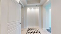 This generously sized single-floor residence offers three bedrooms, three bathrooms, and an expansive, thoughtfully designed layout. The entryway makes a strong first impression with its tray ceiling, recessed lighting, and striking geometric-patterned tile inlay set against neutral large-format flooring. The open kitchen is a standout, showcasing grey shaker-style cabinetry, subway tile backsplash, quartz countertops, stainless steel appliances, a peninsula with seating, and an elegant globe pendant light — all complemented by light hardwood-style flooring. The combined kitchen and living area flows seamlessly, with the living room featuring a fireplace, ceiling fan, crown molding, and large windows that flood the space with natural light and offer impressive panoramic city views. The generously sized primary bedroom continues the theme of light and openness, with wide windows capturing sweeping skyline views and a ceiling fan overhead. It connects to a well-appointed en-suite bathroom with grey cabinetry and quartz surfaces, alongside a spacious walk-in closet outfitted with adjustable shelving and rail systems. Additional bedrooms are equally bright, each with large windows and city views. The residence includes three closets total and four hallways that connect the layout with ease, presenting a clean, modern aesthetic throughout.