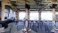 Located at 1301 Washington St in Vicksburg, Mississippi, this single-floor venue offers a dynamic and inviting atmosphere rooted in industrial design. The space is defined by its large, retractable garage-style doors that open fully to frame sweeping panoramic views of the surrounding landscape, flooding the interior with natural light and creating a seamlessly open-air experience.

The dining area is outfitted with high-top tables and metal bar stools arranged throughout, complemented by additional standard seating along the perimeter. Overhead, an exposed ceiling of steel beams and ductwork is adorned with strands of Edison-style string lights, ceiling fans, and mounted flat-screen televisions, striking a balance between industrial edge and casual comfort. Wall-mounted artwork and signage add personality and local character to the space.

The open layout promotes a convivial, social atmosphere suited for both casual dining and group gatherings. Condiment caddies on each table and the relaxed seating arrangement reflect a laid-back, approachable dining concept. The combination of abundant natural light, open views, and a well-considered industrial aesthetic makes this venue a distinctive destination in the Vicksburg area.