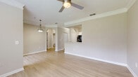 Located in Largo, Florida, this one-bedroom, one-bathroom unit offers a well-designed single-floor layout that maximizes every inch of its space. The open-concept living and dining area features light wood-style flooring, crown molding, and a ceiling fan, creating a bright and airy atmosphere. A pass-through counter connects the living area to the kitchen, which is equipped with white cabinetry, granite countertops, stainless steel appliances including a refrigerator, range, microwave, and dishwasher, complemented by a tile backsplash and additional open shelving for storage. Arched doorways add a subtle architectural detail throughout the common areas. The bedroom is carpeted for comfort, features a ceiling fan, a window with natural views of surrounding greenery, and includes a closet with sliding doors. A second carpeted room, accessible from the hallway, also benefits from natural light and a ceiling fan. The bathroom is outfitted with wood-style tile flooring, a full tub-shower combination, and a vanity with granite countertops and white cabinetry. Neutral tones throughout the space lend a clean, cohesive look.