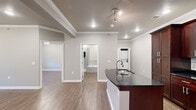 Located in Little Rock, AR, this thoughtfully designed one-bedroom, one-bathroom residence offers a comfortable and modern living experience across a single floor. The open-concept layout seamlessly connects the kitchen and living room, creating a welcoming, functional space. The kitchen is a standout feature, boasting rich dark wood cabinetry that extends to the ceiling, dark granite countertops, a subway tile backsplash, stainless steel appliances, and a curved peninsula island with an undermount sink — ideal for both cooking and casual dining. The living room is bright and inviting, highlighted by a fireplace with a tiled hearth and white mantel, a ceiling fan, crown molding, and sliding glass doors that allow natural light to pour in. Wood-look plank flooring runs consistently throughout the entire space, adding warmth and cohesion. The bedroom is a comfortable retreat, featuring crown molding, a ceiling fan, a closet, and a window with blinds. The full bathroom is well-appointed with a separate glass-enclosed shower, a soaking tub with tile surround, dark wood vanity cabinetry with granite countertops, and wood-look flooring. Crown molding and neutral gray tones are consistent throughout, lending the space a clean, polished aesthetic.
