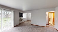 This 2-bedroom, 1-bathroom residence is thoughtfully laid out across a single floor, offering a practical and comfortable living environment. The living area features soft wall-to-wall carpeting, neutral-toned walls, and a sliding glass door fitted with vertical blinds that invites natural light and provides outdoor access. A small built-in shelf with dark cabinetry above it serves as a convenient transitional feature between the living and dining areas. The dining area is defined by light wood-style flooring and a brushed nickel pendant light, creating a clean and cohesive aesthetic. The kitchen is equipped with dark espresso-toned cabinetry, granite-look countertops, and a full suite of stainless steel appliances including a gas range, microwave, and refrigerator, all centered around a U-shaped layout with a window above the sink. The generously sized primary bedroom features plush carpeting, a closet, and direct access to the full bathroom, which includes a dark wood-framed vanity mirror, a granite-style countertop, and tiled walls. The second bedroom offers carpeted flooring, a wide window with blinds, and its own closet. A hallway connects all rooms efficiently, completing this well-organized and move-in-ready home.