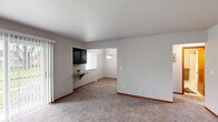 This 2-bedroom, 1-bathroom residence is thoughtfully laid out across a single floor, offering a practical and comfortable living environment. The living area features soft wall-to-wall carpeting, neutral-toned walls, and a sliding glass door fitted with vertical blinds that invites natural light and provides outdoor access. A small built-in shelf with dark cabinetry above it serves as a convenient transitional feature between the living and dining areas. The dining area is defined by light wood-style flooring and a brushed nickel pendant light, creating a clean and cohesive aesthetic. The kitchen is equipped with dark espresso-toned cabinetry, granite-look countertops, and a full suite of stainless steel appliances including a gas range, microwave, and refrigerator, all centered around a U-shaped layout with a window above the sink. The generously sized primary bedroom features plush carpeting, a closet, and direct access to the full bathroom, which includes a dark wood-framed vanity mirror, a granite-style countertop, and tiled walls. The second bedroom offers carpeted flooring, a wide window with blinds, and its own closet. A hallway connects all rooms efficiently, completing this well-organized and move-in-ready home.