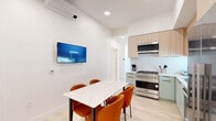 Located in the heart of Los Angeles, this modern single-floor residence at 360 N Hayworth Ave offers six bedrooms and three well-appointed bathrooms. The open kitchen is a standout feature, equipped with stainless steel Viking appliances including a professional gas range and French door refrigerator, complemented by sage green lower cabinetry, light wood upper cabinets, and crisp white countertops. A wall-mounted mini-split system provides efficient climate control, while recessed lighting and a wall-mounted TV enhance the adjoining dining area, which features a marble-top table surrounded by warm amber chairs. The bedrooms maintain a clean, minimalist aesthetic with bright white walls, light hardwood flooring, and large windows that invite natural light and offer neighborhood views. The three bathrooms are finished with large-format white tile flooring, textured wave-patterned wall tiles, floating wood vanities with black fixtures, and frameless glass-enclosed walk-in showers. Two hallways connect the well-organized layout efficiently. Throughout the residence, a consistent modern design language — defined by neutral tones, quality materials, and functional details — creates a cohesive and comfortable living environment.