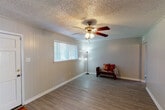 Located at 915 South College Road in Lafayette, Louisiana, this single-floor home offers a practical and comfortable layout designed for everyday living. The main living area greets you with durable wood-look flooring, neutral-toned vertical panel walls, and a textured ceiling complete with a classic ceiling fan and light fixture. A wide window allows natural light to fill the space, creating a bright and welcoming atmosphere. An adjacent area serves as a second living or flex space, featuring the same flooring and another ceiling fan, with a large window overlooking the outdoors. The kitchen is well-appointed with warm honey-toned wood cabinetry, dark granite-style countertops, a double stainless steel sink, and ample upper and lower cabinet storage. The bedrooms are carpeted for comfort, each equipped with ceiling fans and offering a calm, neutral palette with generous floor space. The bathroom includes a full tub-shower combination, toilet, vanity with white cabinetry, wood-look flooring, and a high window for natural ventilation and light. The overall layout is efficient and cohesive, making this Lafayette home a solid and functional residence.