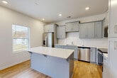 Located at 216 Meyers Ridge Rd in Cramerton, NC, this well-appointed two-story home offers four bedrooms, three bathrooms, and a thoughtfully designed layout across two floors. The main level features an open-concept living room, dining room, and kitchen, where warm hardwood-style flooring flows throughout. The kitchen is a standout, showcasing gray shaker cabinetry, white quartz countertops, a subway tile backsplash, stainless steel appliances including a French door refrigerator and dishwasher, and a central island with bar seating — all bathed in natural light from nearby windows. An attached garage with a concrete floor and electrical panel provides practical utility. Upstairs, the expansive primary bedroom offers generous proportions and plush carpeting, complemented by a private en-suite bathroom featuring gray vanity cabinetry with gold hardware, white quartz countertops, tile flooring, and a glass-enclosed walk-in shower. Three additional bedrooms, also carpeted, share well-appointed bathrooms. A dedicated office, convenient upper-level laundry room, multiple closets, and a patio round out this functional and modern home's offerings.
