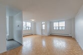 Located at 30 Carabob Ct in Toronto's Scarborough district, this single-floor, two-bedroom, one-bathroom unit offers a well-organized layout across a comfortable footprint. The living area is notably spacious, featuring warm parquet flooring in a classic herringbone pattern and multiple windows that invite generous natural light and outdoor views of the surrounding neighbourhood. Baseboard heating runs along the perimeter walls throughout, ensuring consistent warmth. The kitchen is finished with crisp white cabinetry, a white subway tile backsplash, light countertops, and white tile flooring. It is equipped with stainless steel appliances, including a range, microwave, and dishwasher, providing a functional and clean aesthetic. An adjacent area offers additional open space suitable for dining. The primary bedroom is a well-proportioned room with a large sliding mirrored closet and parquet flooring, while the second bedroom also features parquet floors and a window with outdoor views. The bathroom includes a full soaker tub with an overhead shower, framed by white horizontal subway tile surround. Throughout the unit, white walls and clean finishes create a bright, neutral ambiance.