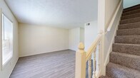 This two-story residence is organized across two comparably sized floors, offering a practical and efficient layout. The main level houses the combined living and dining area, kitchen, and one bathroom. The living room features light wood-look plank flooring and neutral walls, creating a bright, clean atmosphere. Adjacent to it, the dining area is highlighted by a pendant light fixture and a sliding glass door that opens to an outdoor view, allowing natural light to fill the space. The galley-style kitchen is equipped with warm oak cabinetry, light countertops, a double sink, and white appliances including a range, refrigerator, and dishwasher, complemented by a small window above the sink.

The upper floor accommodates both bedrooms, a hallway, two closets, and a second bathroom. The primary bedroom offers a comfortable footprint with carpet flooring and a window framing outdoor greenery. The second bedroom is similarly carpeted and naturally lit. Both bathrooms feature wood-look tile flooring, with at least one including a tub-shower combination and clean white fixtures. A white-banistered staircase connects the two levels, adding a traditional architectural detail to the interior.