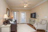 Located on Eastland Court SE in Rome, Georgia, this single-floor residence offers a thoughtfully designed layout that balances comfort and functionality. The living room serves as the heart of the home, featuring elegant crown molding, hardwood-style flooring, a ceiling fan, and large windows dressed with grommet-top curtains that allow natural light to fill the space. A welcoming entry door adds direct accessibility to this area.

The kitchen is outfitted with white cabinetry extending to the ceiling for ample storage, light stone-look countertops, stainless steel appliances including a refrigerator, electric range, and microwave, and hardwood-style flooring. It connects seamlessly to a dedicated dining area, creating a practical and sociable layout ideal for everyday living and entertaining.

The residence includes multiple bedrooms, each finished with neutral tones, plush carpeting, ceiling fans, and natural light from well-placed windows. The primary bedroom is generously proportioned and features multiple windows, while the secondary bedrooms are equally well-appointed with coordinating rustic wood furniture and warm ambient lighting.

The bathroom features a clean, white vanity with stone-look countertops, a lighted mirror, and hardwood-style flooring. Crown molding and consistent neutral tones throughout the home contribute to a cohesive and welcoming ambiance.