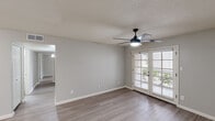 This 2-bedroom, 2-bathroom single-floor residence offers a thoughtfully designed layout with a clean, modern aesthetic throughout. Wood-look plank flooring flows continuously across all living areas, complemented by neutral gray walls and crisp white trim that create a bright, cohesive feel.

The combined kitchen and living area serves as the heart of the home. The galley-style kitchen is equipped with white cabinetry, light stone-finish countertops, stainless steel appliances including a refrigerator and dishwasher, and a built-in sink with ample counter space. An adjacent dining or living area features a ceiling fan with lighting and leads to the outdoors through a set of French doors, inviting natural light and outdoor views.

Both bedrooms are generously proportioned, each featuring a ceiling fan with light fixture and windows with exterior views. The primary bedroom is notably spacious and includes direct access to a well-organized walk-in closet with built-in shelving and dual hanging rods for efficient storage.

The two bathrooms are finished consistently, each featuring white vanity cabinetry, stone-look countertops, large mirrors, and a tub-shower combination with tile surround. A hallway connects the private areas of the home, and a dedicated closet provides additional storage. The overall ambiance is clean, neutral, and move-in ready.