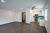 Located at 126 E 18th St in Costa Mesa, California, this single-floor unit offers a clean, modern aesthetic throughout its open layout. The living area is bright and spacious, finished with light wood-look flooring that extends seamlessly throughout the space. Recessed lighting and a ceiling fan provide both illumination and comfort, while multiple windows dressed with horizontal blinds and a sliding glass door with vertical blinds invite natural light and offer outdoor access.

The kitchen is a standout feature, designed with sleek white cabinetry, light-toned countertops, and a bold turquoise backsplash that adds a vibrant pop of color. Stainless steel appliances, including a gas range and over-the-range microwave, equip the kitchen for everyday use. A stainless steel sink and ample counter space round out the functional design.

The living space features crisp white walls, gray baseboards, and a textured ceiling, contributing to a fresh and well-maintained interior. A wall-mounted HVAC unit provides climate control. The overall ambiance is clean, contemporary, and move-in ready, reflecting a thoughtfully updated interior well-suited to the Southern California lifestyle.