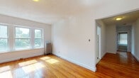 Located at 119 W Wyoming Ave in Melrose, MA, this single-floor unit offers a bright, well-organized layout with a clean, neutral aesthetic. Warm hardwood floors run continuously throughout the living areas, bedrooms, and hallway, lending a cohesive and inviting character to the entire space.

The living areas are generously proportioned, benefiting from multiple double-hung windows that invite abundant natural light and offer views of the surrounding neighborhood. Classic cast-iron radiators provide reliable heating in several rooms, a hallmark of traditional New England construction. White walls and clean trim work keep the interiors feeling fresh and airy.

The galley-style kitchen is efficiently arranged with wooden cabinetry, a gas range, refrigerator, and a stainless steel sink, with direct access to additional areas of the unit. The bathroom features classic white subway tile with a decorative border accent, a full soaking tub with an overhead shower, and a window for natural ventilation.

The bedrooms are well-sized, each with ample natural light. One bedroom includes two closets, one of which is a built-in rod closet, offering practical storage. A clean, straight hallway connects the rooms and adds to the efficient flow of the layout. Overall, this unit presents a timeless, functional design rooted in the character of its Melrose neighborhood setting.
