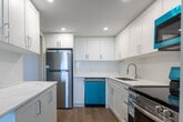 Located at 200 Denistoun St in Welland, Ontario, this well-appointed one-bedroom, one-bathroom unit offers a comfortable and thoughtfully designed single-floor layout. The open-concept living and dining area is bright and airy, featuring light-toned laminate wood flooring, neutral grey walls, and a textured ceiling. Large floor-to-ceiling windows flood the space with natural light and frame sweeping outdoor views of the surrounding greenery — a standout feature of the living area.

The kitchen has been tastefully updated with crisp white shaker-style cabinetry extending to the ceiling, stainless steel appliances including a refrigerator, range, and built-in microwave, a double stainless sink, and recessed lighting — creating a clean and functional cooking space.

The bedroom is a generous size, carpeted for comfort, and includes a full-width sliding door closet offering ample storage. The soft, neutral palette carries throughout, lending the space a calm and cohesive feel. Baseboard heaters are present in the main living areas, and an in-unit air conditioning unit is situated in the living room window. The overall ambiance is clean, modern, and move-in ready, making it a practical and inviting home.