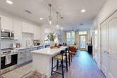 Located at 368 Sublime Summer Lane in Clover, SC, this thoughtfully designed 2-bedroom, 2-bathroom residence offers a comfortable and stylish single-floor layout. The open-concept kitchen and living area serves as the heart of the home, featuring white upper cabinetry, gray lower cabinets, a classic subway tile backsplash, stainless steel appliances, and a white quartz waterfall island with bar seating illuminated by sleek pendant lighting. Wood-look flooring flows throughout, tying the spaces together seamlessly. The living room is bright and inviting, with large windows that welcome abundant natural light, a ceiling fan, and direct access to a private balcony. Both bedrooms are well-sized, offering generous closet space — including a spacious walk-in closet — ceiling fans, and large windows with outdoor views. The primary bathroom features gray cabinetry, a white quartz vanity, and a glass-enclosed shower. Additional conveniences include a dedicated laundry area, a utility room, and ample built-in storage throughout. The clean, neutral palette and modern finishes create a bright, cohesive ambiance ideal for everyday living.