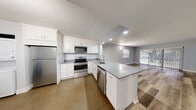 Located at 4797 Lake Arjaro Dr in West Palm Beach, FL, this single-floor, 3-bedroom, 2-bathroom home offers a well-designed layout with modern finishes throughout. The open-concept kitchen and living area serves as the heart of the home, featuring white shaker cabinetry extending to the ceiling, gray quartz-style countertops, a peninsula island, and a full suite of stainless steel appliances including a refrigerator, range, microwave, and dishwasher. Large-format tile flooring anchors the kitchen, while warm wood-look luxury vinyl plank flooring flows through the living areas and bedrooms. The living room is bright and airy, filled with natural light from a large window and sliding glass doors that open to a screened balcony overlooking a lush, green lawn and mature trees. The primary bedroom offers a comfortable footprint with access to a dedicated closet and an adjoining bathroom. The two additional bedrooms are well-proportioned with windows providing natural light. Both bathrooms are clean and functional with modern fixtures. A hallway connects the private sleeping quarters to the main living spaces, completing this practical and refreshed single-story home.