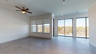 Located at 11922 S I-35 Frontage Rd in Austin, TX, this modern single-floor residence offers a thoughtfully designed layout with contemporary finishes throughout. The open-concept living area is bright and airy, featuring wood-look flooring, a ceiling fan, and an abundance of natural light streaming through a triple window bank and full-height sliding glass doors that open to an outdoor balcony with scenic tree line views. The kitchen is a standout space, centered around a large island with an undermount sink and quartz countertops. Grey shaker-style cabinetry reaches to the ceiling, complemented by a marble-look backsplash, pendant lighting, and a full suite of stainless steel appliances including a refrigerator, range, and over-the-range microwave. The bedrooms offer comfortable proportions with wood-look flooring, ceiling fans, and generous closet space — one featuring a walk-in closet with built-in shelving. Two bathrooms serve the residence: one with a dual-sink vanity featuring quartz countertops, a glass-enclosed walk-in shower, and modern fixtures; the other with a single-sink vanity and a soaking tub with tile surround. Clean white walls and recessed lighting throughout create a cohesive, move-in-ready aesthetic.