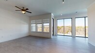 Located at 11922 S I-35 Frontage Rd in Austin, TX, this modern single-floor residence offers a thoughtfully designed layout with contemporary finishes throughout. The open-concept living area is bright and airy, featuring wood-look flooring, a ceiling fan, and an abundance of natural light streaming through a triple window bank and full-height sliding glass doors that open to an outdoor balcony with scenic tree line views. The kitchen is a standout space, centered around a large island with an undermount sink and quartz countertops. Grey shaker-style cabinetry reaches to the ceiling, complemented by a marble-look backsplash, pendant lighting, and a full suite of stainless steel appliances including a refrigerator, range, and over-the-range microwave. The bedrooms offer comfortable proportions with wood-look flooring, ceiling fans, and generous closet space — one featuring a walk-in closet with built-in shelving. Two bathrooms serve the residence: one with a dual-sink vanity featuring quartz countertops, a glass-enclosed walk-in shower, and modern fixtures; the other with a single-sink vanity and a soaking tub with tile surround. Clean white walls and recessed lighting throughout create a cohesive, move-in-ready aesthetic.