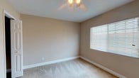 Located in the Eden Isle neighborhood of Saint Petersburg, Florida, this single-story home offers a functional and well-organized layout. The spacious living area greets you at the entrance, featuring neutral-toned carpet, large windows on either side of the front door that flood the space with natural light, and tile flooring at the entry threshold. The kitchen is equipped with warm-toned wood cabinetry, a stainless steel sink, tile flooring, and black appliances including a refrigerator and range. Bedrooms are finished with plush carpeting, ceiling fans, and window blinds that allow for controlled natural light. The primary bedroom is notably well-appointed, featuring multiple closets including a walk-in, providing generous storage. Additional bedrooms share a similar neutral palette and comfortable design. The bathroom includes a full tub/shower combo with tile flooring and a textured wall finish. Throughout the home, consistent warm beige tones, white trim, and ceiling fans contribute to a cohesive and comfortable atmosphere suited to the Florida climate.