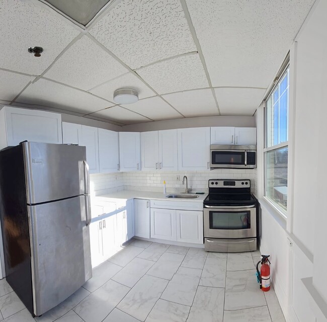 Kitchen with stainless steel appliances, double paned window next to stove for fresh airflow. - 5 E Broad St