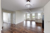 This thoughtfully designed one-bedroom, one-bathroom residence offers a comfortable and functional layout across a single floor. Rich, dark hardwood-style flooring flows seamlessly throughout every room, creating a warm and cohesive aesthetic.

The open-concept living and kitchen area forms the heart of the home. The kitchen is well-equipped with white shaker-style cabinetry, granite countertops, stainless steel appliances including a range, microwave, and dishwasher, and a peninsula that doubles as additional prep and dining space. A pendant light overhead adds a refined accent. Multiple windows along the exterior wall flood the space with natural light and offer views of the surrounding neighborhood.

The living area is generously proportioned with clean white walls and exposed structural beam details that add architectural character. Large windows continue the theme of brightness and openness.

The bedroom is a comfortable, private retreat featuring a sliding-door closet with built-in shelving and a window with neighborhood views. The bathroom includes a full soaking tub and shower combination with clean, bright finishes.

Throughout the residence, the neutral color palette, modern fixtures, and consistent flooring create a cohesive and inviting atmosphere suited for everyday living.