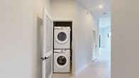 Located at 150 S Bryan Rd in Dania Beach, FL, this modern single-floor residence offers 2 bedrooms and 2 bathrooms with a clean, contemporary design aesthetic. Light wood-style flooring runs throughout the home, complementing the bright white walls and creating a cohesive, airy feel.

The open-concept kitchen is a standout feature, showcasing a two-tone design with dark wood-grain lower cabinetry and crisp white upper cabinets that extend to soaring ceiling heights. Stainless steel appliances — including a French door refrigerator, range, microwave, and dishwasher — add a polished, functional touch. Horizontal clerestory windows and a larger kitchen window frame views of swaying palm trees, flooding the space with Florida sunshine.

Both bedrooms are bright and well-proportioned, with large black-framed windows offering lush, green outdoor views. The primary bedroom includes a closet with double doors featuring sleek black hardware. Each bathroom is thoughtfully appointed with wood-toned floating vanities, white quartz countertops, undermount sinks, and glass-enclosed walk-in showers with neutral tile surround. A connecting hallway links the living spaces efficiently. The overall ambiance is modern, minimal, and move-in ready.