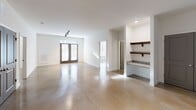 Located at 8700 Seeing Trail Rd in Wake Forest, NC, this 2-bedroom, 1-bathroom unit offers a thoughtfully designed single-floor layout with a clean, modern aesthetic throughout. Polished concrete floors run continuously across the entire space, lending an industrial-chic character that ties each room together seamlessly.

The kitchen is a standout feature, equipped with grey shaker-style cabinetry, granite countertops, a subway tile backsplash, a stainless steel farmhouse sink, and a full suite of stainless steel appliances including a refrigerator, range, microwave, and dishwasher. A built-in wine rack adds a distinctive finishing touch. Track lighting overhead ensures excellent task illumination.

The open living area benefits from natural light through large windows and French doors, complemented by built-in shelving for added functionality. Ceiling fans are present in both bedrooms, which feature bright white walls and polished concrete floors. The primary bedroom is generously sized and includes access to two closets outfitted with wire shelving systems for organized storage.

The bathroom is well-appointed with a grey vanity, granite countertop, an illuminated mirror, overhead cabinetry, and a glass-enclosed shower. The overall ambiance is modern, clean, and functional, making this a well-equipped space in the heart of Wake Forest.