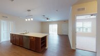 Located at 20 House Ave in Camp Hill, Pennsylvania, this single-floor residence offers a well-designed, open-concept layout that maximizes functionality and comfort. The kitchen is a standout feature, outfitted with rich dark cabinetry, stainless steel appliances including a refrigerator, range, and over-the-range microwave, white quartz-style countertops, a subway tile backsplash, and a central island with pendant lighting and built-in shelving. The kitchen flows seamlessly into a generously sized living area with hardwood-style flooring, crown molding, a ceiling fan, and access to an outdoor balcony through sliding glass doors. The bedroom is carpeted and bright, featuring a ceiling fan and natural light from a large window with exterior views. The bathroom is well-appointed with a vessel sink atop a dark wood vanity, white countertop, a framed mirror with overhead vanity lighting, and tile flooring. A half bath with tile flooring provides additional convenience. The dedicated laundry room houses a full-size washer and dryer with overhead wire shelving for storage. Throughout the residence, warm neutral tones and consistent finishes create a cohesive and inviting atmosphere.