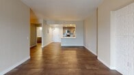 This single-floor unit offers a thoughtfully designed layout with contemporary finishes and functional living spaces. The open-concept living area is anchored by large-format tile flooring and a striking accent wall with white brick-style tile, complemented by a sliding glass door that invites natural light and provides access to an outdoor balcony fitted with classic plantation shutters.

The kitchen is well-equipped and modern, featuring stainless steel appliances including an electric range, over-the-range microwave, and refrigerator. Sleek wood-grain cabinetry extends to the ceiling, accented by a blue glass tile backsplash, while a peninsula with a white countertop and integrated sink adds both prep space and a natural divider from the main living area. Recessed lighting illuminates the kitchen efficiently.

The bedroom is a comfortable, quiet retreat with warm wood-look flooring and a full-width mirrored sliding closet that enhances the sense of space while providing ample storage with a built-in shelving and rod system.

The bathroom is clean and functional, featuring a full tub-shower combination surrounded by classic white square tile, a floating wood-grain vanity with white countertop and undermount sink, polished chrome fixtures, and a large wall mirror. Wood-look tile flooring ties the space together cohesively. A stacked washer and dryer are also included within the unit, adding everyday convenience.
