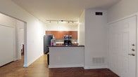 This 1-bedroom, 1-bathroom residence offers a thoughtfully designed single-floor layout that maximizes every square foot. The open-concept kitchen serves as a central feature, equipped with rich cherry-toned cabinetry, granite-style countertops, a tile backsplash, and a full suite of black and stainless steel appliances including a refrigerator, electric range, and over-the-range microwave. A peninsula counter provides a natural divide between the kitchen and the living area, enhancing the sense of openness. Hardwood-style flooring flows consistently throughout the main living spaces, adding warmth and visual continuity. The living room is bright and airy, featuring a ceiling fan with light fixture and French doors that open to a private balcony with views of surrounding greenery. The bedroom is a comfortable, well-proportioned retreat with its own ceiling fan, a large window framing lush outdoor scenery, and hardwood-style flooring. The bathroom is clean and functional, featuring a full tub-shower combination with white tile surround, a vanity with matching granite-style countertop, and consistent wood-look flooring. Neutral wall tones and track lighting in the kitchen contribute to a modern, cohesive aesthetic throughout the space.