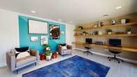Located at 9757 E Colorado Ave in Aurora, Colorado, this single-floor community space showcases a thoughtfully designed interior with a bold mid-century modern aesthetic. The layout flows seamlessly between distinct functional zones, creating an inviting and versatile environment.

The lounge area serves as a central hub, anchored by a striking teal accent wall adorned with a curated gallery of framed artwork. Comfortable gray upholstered armchairs are arranged around warm wooden side tables and planters, while a vibrant blue area rug grounds the space. A geometric, open-frame bookshelf in warm wood adds visual interest and a touch of whimsy.

Adjacent to the lounge, a built-in workstation features floating wooden shelves set against a textured honeycomb tile wall, accompanied by a desk and ergonomic chair — ideal for focused work or study. Recessed lighting illuminates the area evenly throughout.

A dedicated meeting and dining area showcases a solid wood table surrounded by colorful seating, bathed in natural light streaming through large black-framed windows that frame lush outdoor greenery and a tranquil water feature. Industrial-style pendant lights hang above, completing the modern look.

The entrance features a glass-paneled door that floods the space with daylight, with a wall-mounted coat rack and climate control unit nearby. Light wood-look tile flooring unifies the entire space, contributing to the clean, contemporary feel throughout.