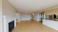 This single-floor residence offers a thoughtfully designed open-concept layout with a generous living and dining area at its heart. Light-toned hardwood flooring flows throughout the main living spaces, complemented by warm beige walls and white trim that create a clean, welcoming ambiance. A classically styled fireplace with a white mantel serves as a striking focal point in the living room, adding both character and comfort to the space.

The kitchen is open to the main living area and features light maple cabinetry, dark countertops, stainless steel appliances including a refrigerator, electric range, and microwave, as well as a double stainless steel sink and a dishwasher. A peninsula counter with an overhang connects the kitchen to the living space, making it ideal for casual dining or entertaining.

The bedroom is carpeted and bathed in natural light from a large window offering outdoor views. The full bathroom is finished with light ceramic tile flooring, a wide white vanity with ample drawer storage, a large mirror, and a shower-tub combination. A dedicated in-unit laundry closet houses a stacked washer and dryer for added convenience. Together, these features make for a well-appointed, functional, and comfortable living space.