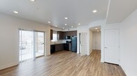 This single-floor residence showcases a clean, contemporary design throughout. The open-concept living and kitchen area is anchored by warm hardwood-style flooring that extends seamlessly across the space, complemented by recessed lighting overhead that creates a bright, welcoming atmosphere. A sliding glass door with vertical blinds opens to a private balcony, allowing natural light to fill the main living area and providing outdoor access.

The kitchen features dark espresso-toned cabinetry with ample storage, a stainless steel sink, and a full suite of black appliances including a refrigerator, range, microwave, and dishwasher. An arched hallway transitions from the main living space to the additional rooms, adding an architectural detail that softens the overall layout.

The remaining rooms continue the consistent flooring and neutral color palette, with each space benefiting from multiple windows fitted with horizontal blinds that allow for adjustable natural light. Recessed lighting is present throughout, maintaining a cohesive and modern aesthetic. The overall ambiance is clean, bright, and move-in ready, offering a practical yet polished living environment.